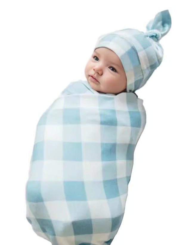Newborn swaddled in blue gingham blanket wearing the matching knotted hat