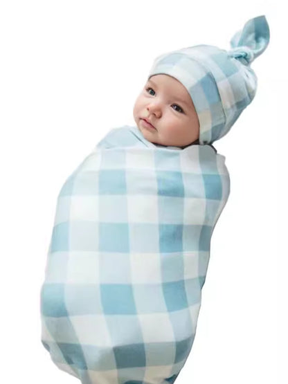 Newborn swaddled in blue gingham blanket wearing the matching knotted hat