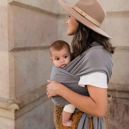 Parent wearing the grey baby wrap carrier with baby held close to the chest