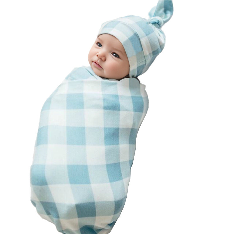 Newborn baby wrapped in sky blue gingham swaddle with matching knotted hat