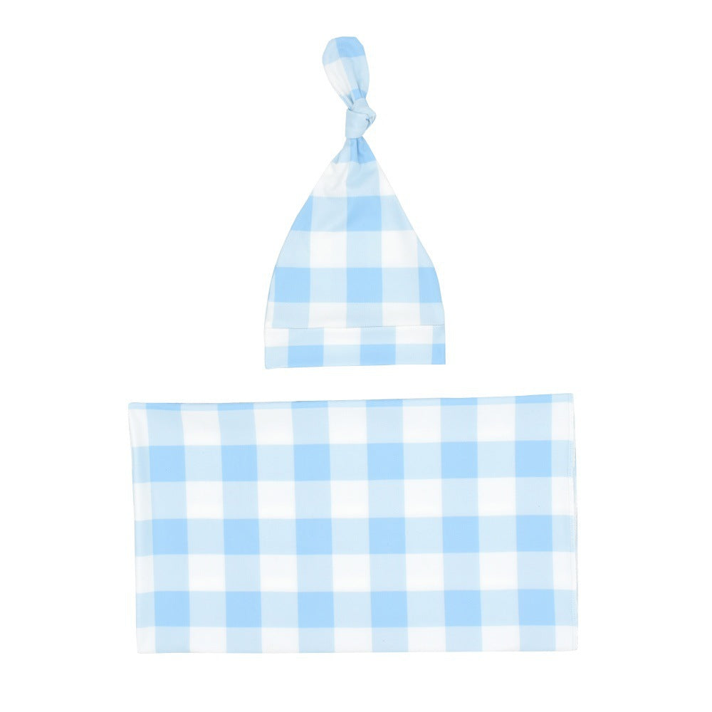 Light blue gingham swaddle blanket and knotted baby hat laid flat
